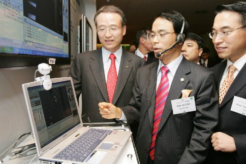 2005년 11월, 진대제 당시 정보통신부 장관(가운데)이 당시 남중수 KT 사장(왼쪽), 과 당시 홍원표 KT휴대인터넷사업본부장과 와이브로를 시연해 보고 있다. (사진=정보통신부(현, 과학기술정보통신부))