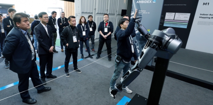 라스베이거스에서 개최된 CES 2019에서 네이버 부스에 방문한 노진서 LG전자 로봇사업센터장 (전무, 왼쪽에서 세번째)을 비롯한 관계자들이 5G 브레인리스 로봇 앰비덱스의 시연을 지켜보고 있다. (사진제공=네이버)
