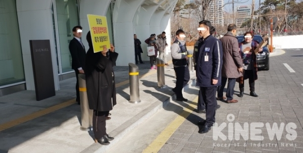 박민정 피해자연합회 회원(AK내셔날 대표)이 피켓을 들고 롯데타워 건물 앞에 서 있다. 경찰청 공보관과 대치하고 있는 모습. (사진=신민경 기자)