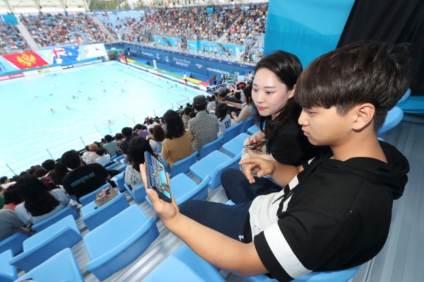 광주세계수영선수권대회 참석한 관람객들이 KT 5G 네트워크를 이용해 핸드폰으로 경기 동영상을 감상하고 있다 (사진=KT)