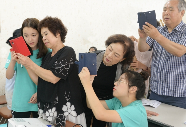 8월1일 용문종합사회복지관에서 대전 탄방중학교 이은제 학생(왼쪽에서첫번째)과 서대전여자고등학교 박윤서(왼쪽에서 네번째) 학생이 어르신에게 스마트폰 사용법을 설명하고 있다 (사진=KT)