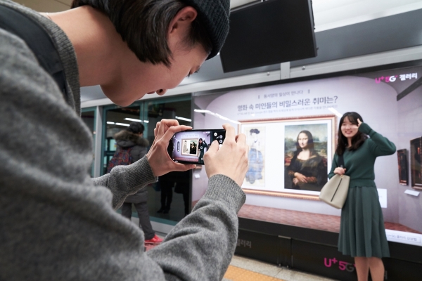 서울 지하철 6호선 공덕역에 마련된 세계 최초 5G기반 문화예술 공간 ’U+5G 갤러리’에 방문한 고객이 ‘U+AR’ 앱으로 작품을 체험하고 감상하고 있다 (사진=LG유플러스)