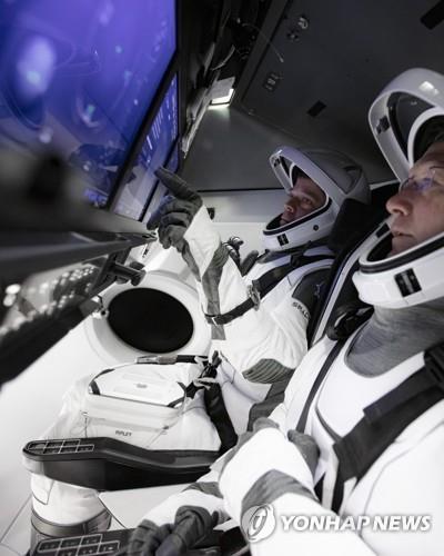 크루 드래건 시뮬레이터 앞의 두 우주 비행사 크루 드래건 캡슐의 첫 유인 비행시험을 맡은 더그 헐리와 봅 벤켄 우주비행사가 터치스크린으로 된 조종판 앞에서 스페이스X 측이 마련한 우주복을 입고 캡슐 작동 훈련을 하고 있다.