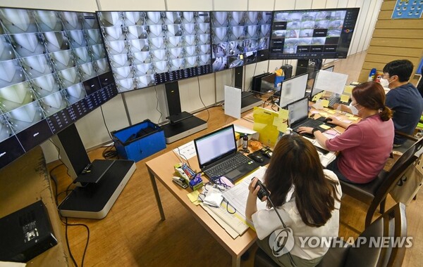 생활치료센터 상황실서 관계자들이 CC(폐쇄회로)TV 관제 모니터를 보며 입실 상황을 살피고 있다. [사진: 연합뉴스]