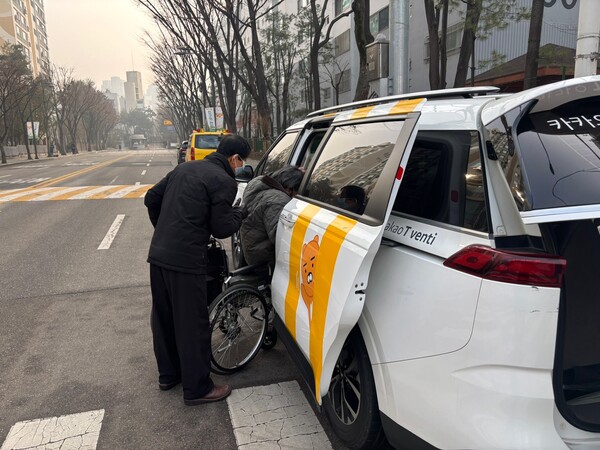 휠체어를 이용하는 승객과 보호자가 카카오T로 호출한 택시에 탑승하고 있다. [사진: 석대건 기자]