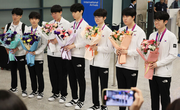 '페이커' 이상혁을 비롯해 2022 항저우 아시안게임에서 금메달을 획득한 '리그 오브 레전드' 대한민국 국가대표 선수들이 인천국제공항 제1여객터미널을 통해 귀국해 메달을 들어보이고 있다. [사진: 연합뉴스]